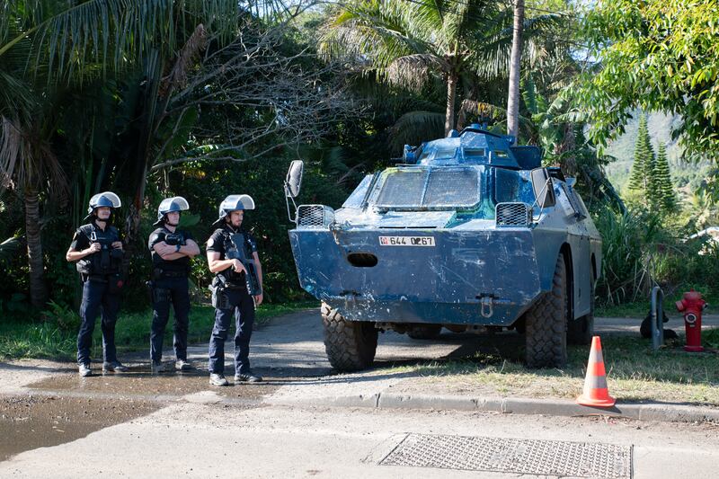 Officers of the gendarmerie nationale stand guard by an armored vehicle at a roadblock set at the northern entrance to the route de Saint-Louis in Mont-Dore, in the French overseas collectivity of New-Caledonia, on Oct. 8, 2024.