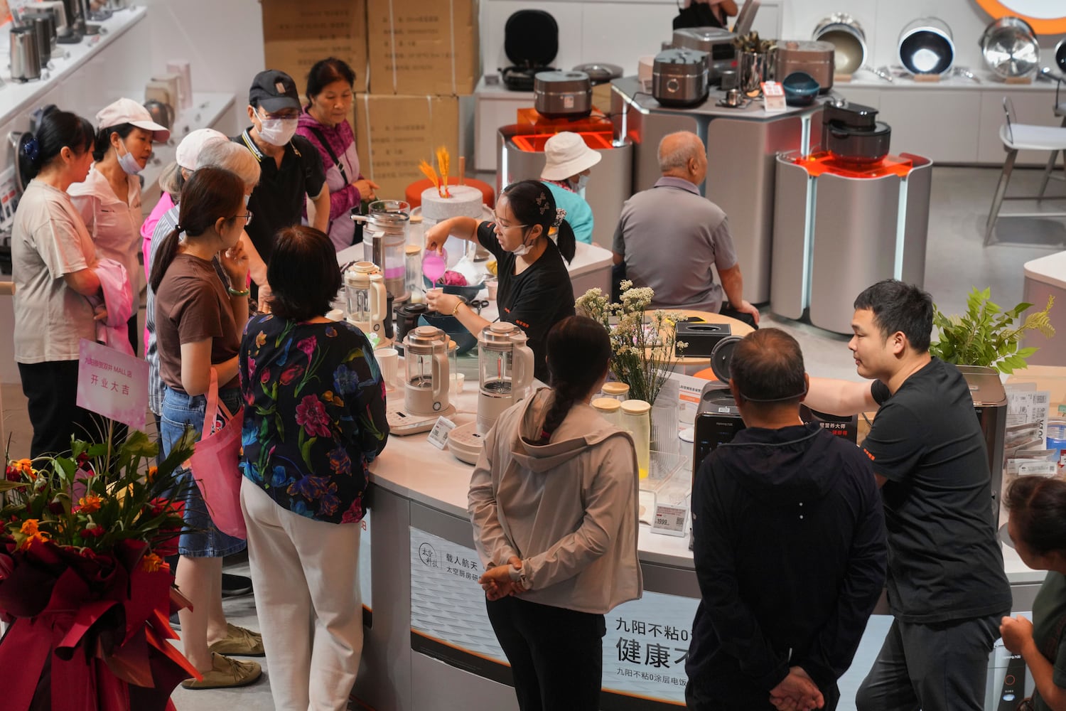 Residents gather to watch a juice mixer machine demonstration at a newly opened Chinese e-commerce platform JD.com shopping mall in Beijing, June 16, 2025.