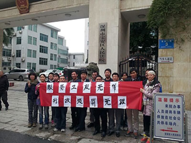 2012年12月4日，深圳市寶安區公益組織“小小草工友家園”的員工及受助工友，在區法院外手持橫幅，要求撤銷消防大隊的禁閉令及歸還一萬元罰款。（小小草提供）