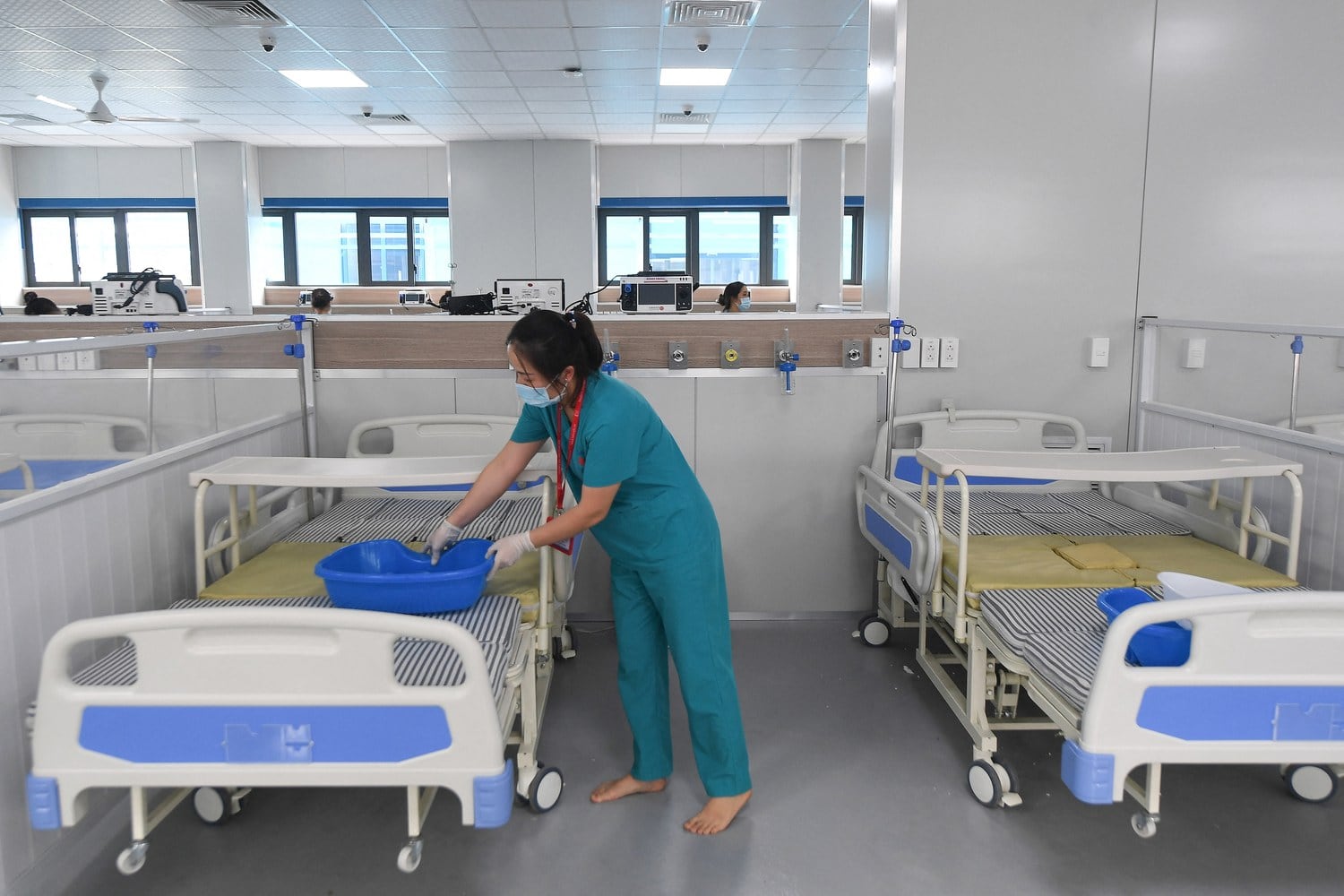 Một nhân viên y tế dọn giường bệnh tại một bệnh viện dã chiến điều trị bệnh nhân COVID-19 ở Hà Nội hôm 30/8/2021. AFP