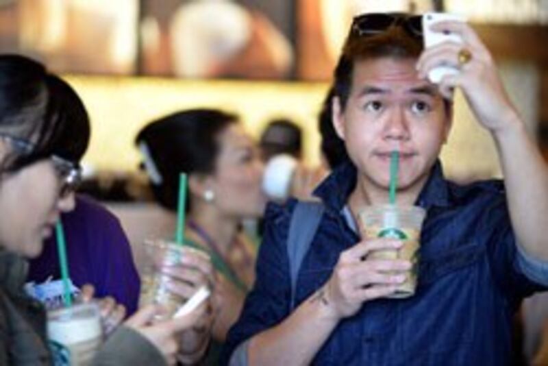 GIới trẻ VN chụp hình ly cà phê Starbucks trong ngày khai trương cửa hàng 01/2/2013. AFP photo