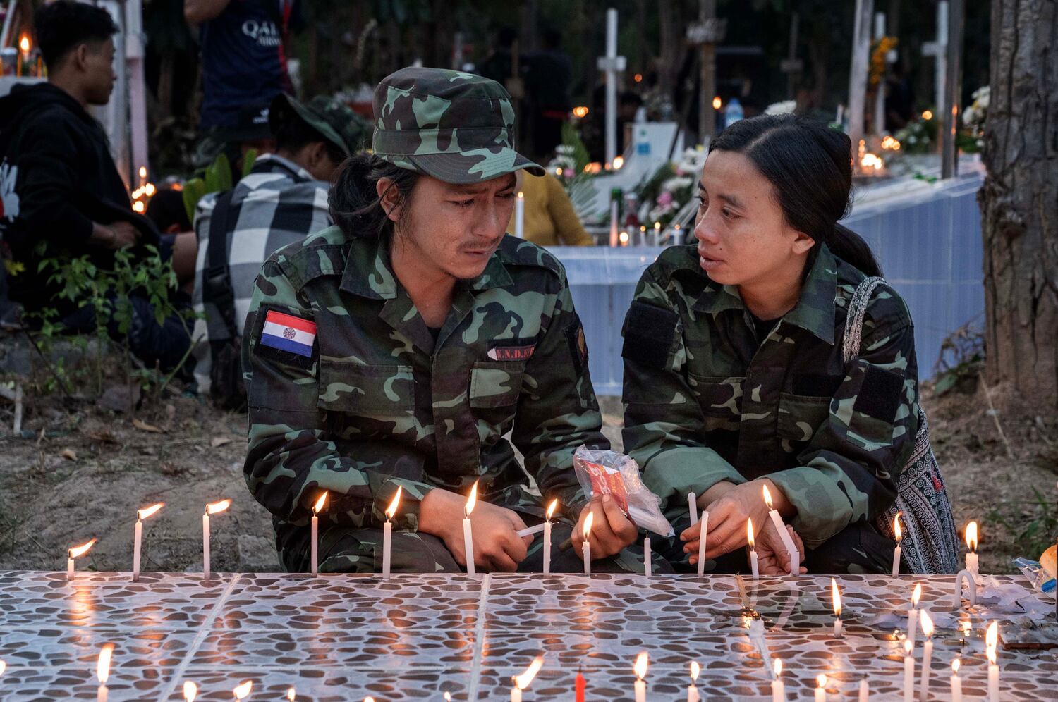 Yan Naing, left, and his wife, Cherry Hlaing, both fighters of KNDF cry over the grave of Naing’s younger brother Myat Min Thu at a martyr’s cemetery to commemorate the fighters who died fighting Myanmar's military in Demoso, Kayah state, Nov. 2, 2024. (RFA)