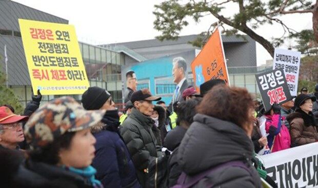 11일 서울 청와대 분수대 앞에서 열린 '문재인 대통령 직무유기고소 관련 기자회견'에서 6·25전쟁납북인사가족협의회 등 참가자들이 김정은 국무위원장의 서울 답방을 반대하는 모습 사이로 문재인 대통령과 김정은 국무위원장의 만남을 그린 벽화가 보이고 있다. 