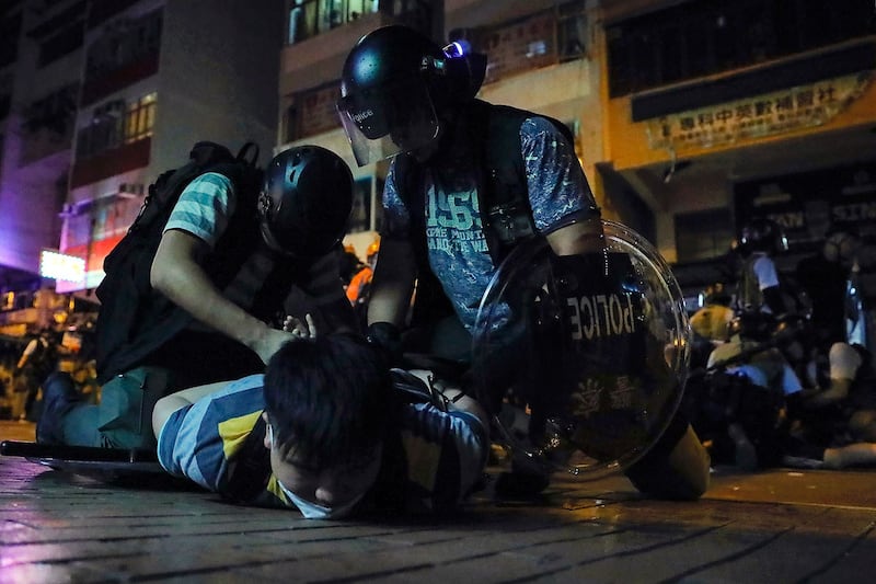 资料图片:2019年8月7日,香港警察在深水埗警署外,一名示威者被警方压在地上逮捕。(美联社)