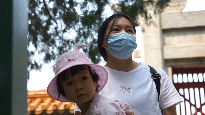 图说:2021 年 5 月 20 日,两个孩子的母亲岳燕(音译)在北京的一个公园里照顾她的一个女儿。 35 岁的岳艳花几天时间照顾 2 岁的孩子,晚上辅导她 10 岁的孩子做作业 。(美联社)