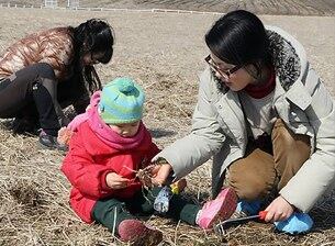 경기도 안성 팜랜드를 방문한 어린이가 가족과 함께 목초지에 심어놓은 냉이를 캐면서 활짝 웃고 있다