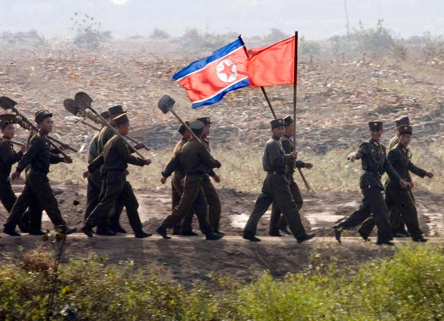북한군 병사들이 삽과 인공기를 들고 신의주 외곽을 행진하고 있다.