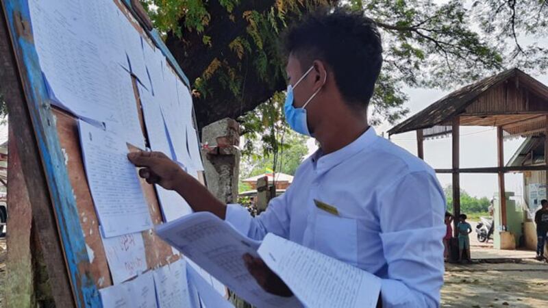 A local election official checks a voter list on a board at a polling station in Dawei township, southern Myanmar's Tanintharyi region, Nov. 8, 2020.