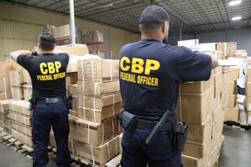 نيۇ-يورك پورتىدىكى ئامېرىكا تاموژنا ۋە چېگرا قوغداش (CBP) خادىملىرى خىتايدىن كىرگەن، ئۇيغۇر رايونىدىكى تۈرمە ياكى جازا لاگېردىكىلەرنىڭ ئەمگىكى بىلەن ياسالغان دەپ گۇمان قىلىنغان يالغان چاچ ۋە قوشۇمچە بۇيۇملارنى تەكشۈرمەكتە. 2020-يىلى 29-ئىيۇن.