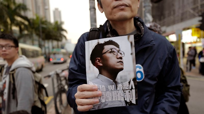 一名香港抗议者手拿梁天琦的照片表示对他的支持。(美联社)