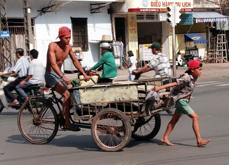 Một bé trai lao động cùng cha tại thành phố Hồ Chí Minh.