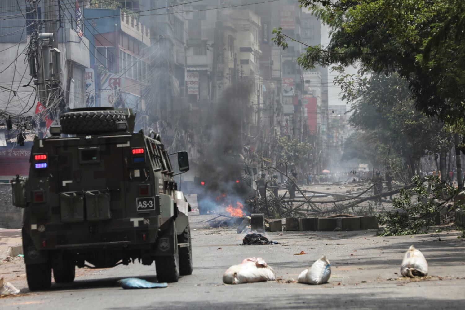 A fire burns as a military vehicle approaches a road block set up by protesters in the Rampura area of Dhaka, July 20, 2024. (Jibon Ahmed/BenarNews)