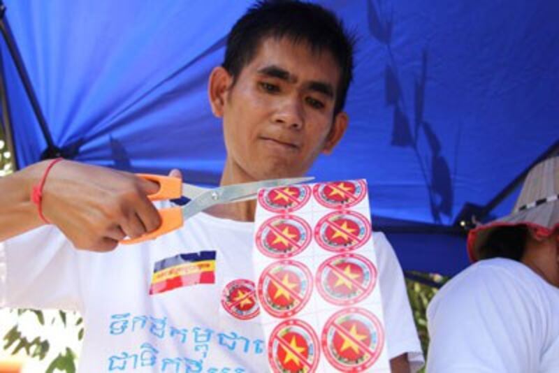 Người biểu tình Campuchia phát logo tẩy chay hàng hóa và dịch vụ của Việt Nam trong cuộc biểu tình trước ĐSQVN ngày 4/10/2014. RFA PHOTO/QUỐC VIỆT. 