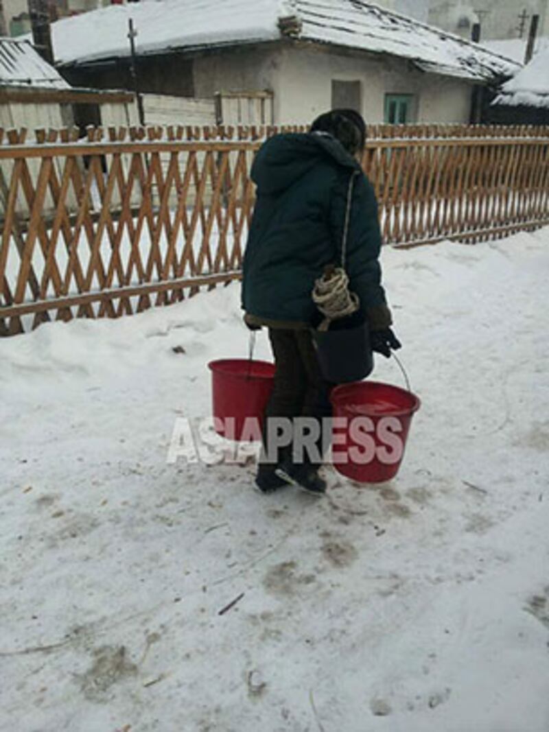 마을 공동 우물에서 물을 긷고 집에 돌아가는 여성. 2015년 1월 북한 중부 지방에서 민들레 촬영. 사진-아시아프레스 제공