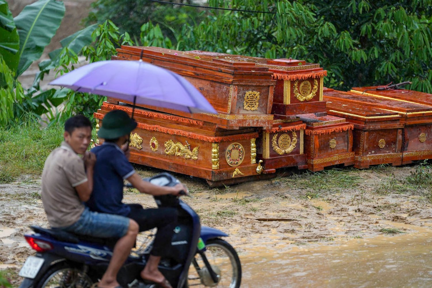 Men on a scooter roll in front of coffins stacked for the victims of a landslide in the mountainous village distant from Lang Naked, the province of Lao Cai, Vietnam, September 11, 2024. (AFP)