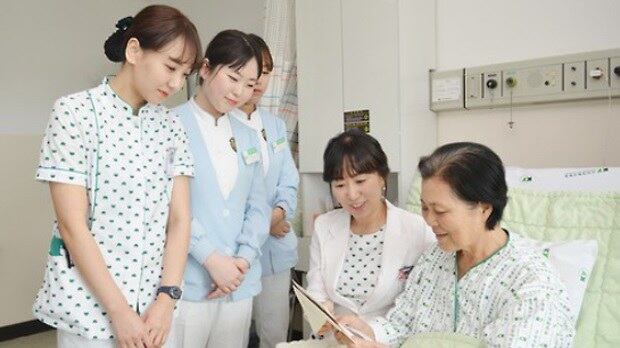 한 환자가 간호사들과 함께 병상에서 쾌유 기원 글을 읽어보고 있다.