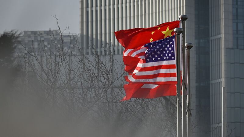 图为，2020年1月18日，中国和美国国旗在北京某公司办公大楼入口处飘扬。（法新社）