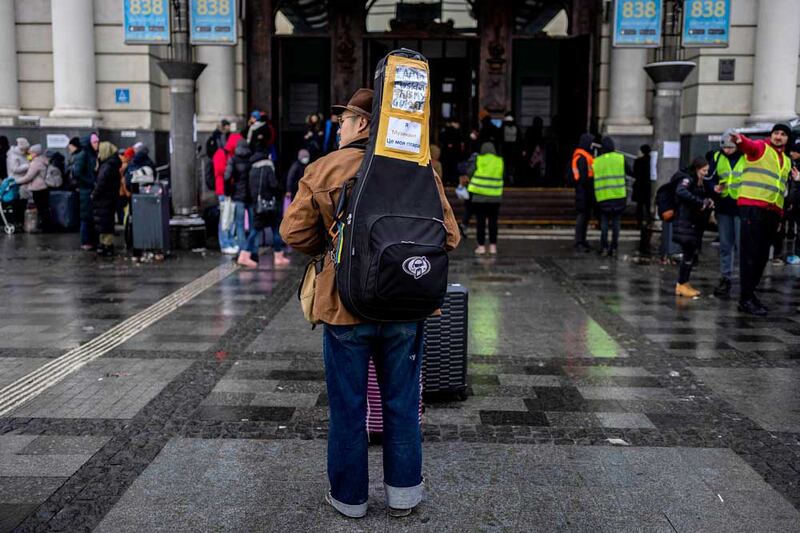 Chinese music student Tian Runnong stands outside Lviv railway station on Feb. 28, 2022, in western Ukraine. The sign on his guitar case reads, "I'm a musician. This is my guitar." (Associated Press)