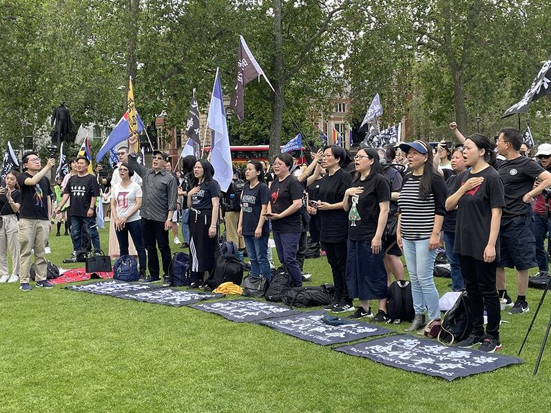 近千名港人酷热下在英国国会大楼前“如水再聚”，无惧港府恐吓，高唱《愿荣光归香港》。不少参加者颂唱时手放胸前，神情凝重。 （吕熙摄）