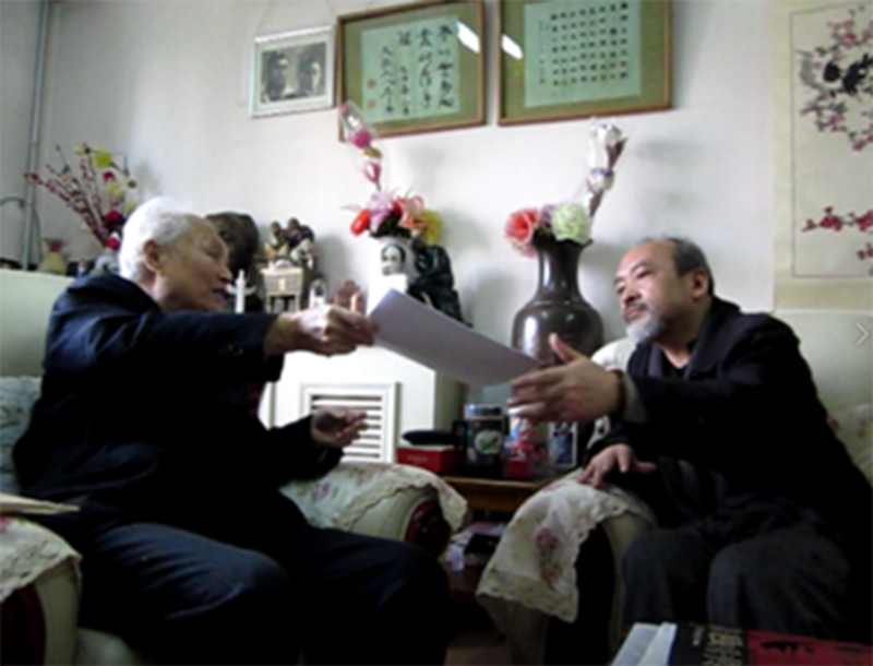 2014年4月24日李锐（左）在自己宅中向来访者王康（右）、北明介绍他刚收到的一份内部文稿：“习仲勋披露胡耀邦下台内幕”。北明现场拍摄/视频截图。