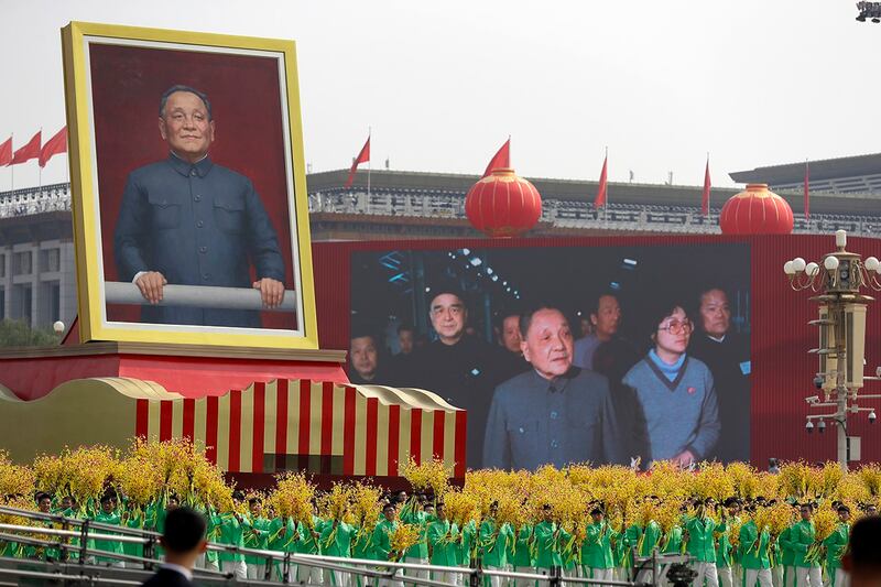 2019年10月1日,中共建政70周年庆典上,持花的游行队伍环绕巨型的邓小平画像。(美联社资料图片)