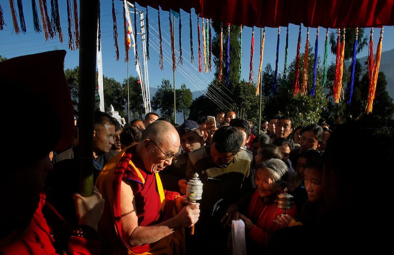 Tibetan spiritual leader the Dalai Lama spins the prayer wheel of a devotee before beginning a three-day long retreat at the Tashiding monastery in Tashiding, in west Sikkim, India, Dec. 16, 2010.