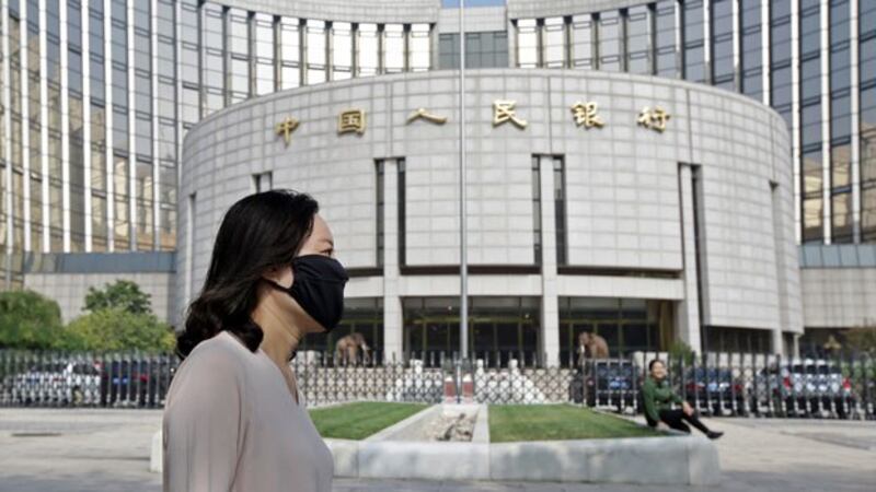 A woman wearing a face mask walks past the headquarters of the People's Bank of China (PBOC), the central bank, in Beijing, Sept. 28, 2018.