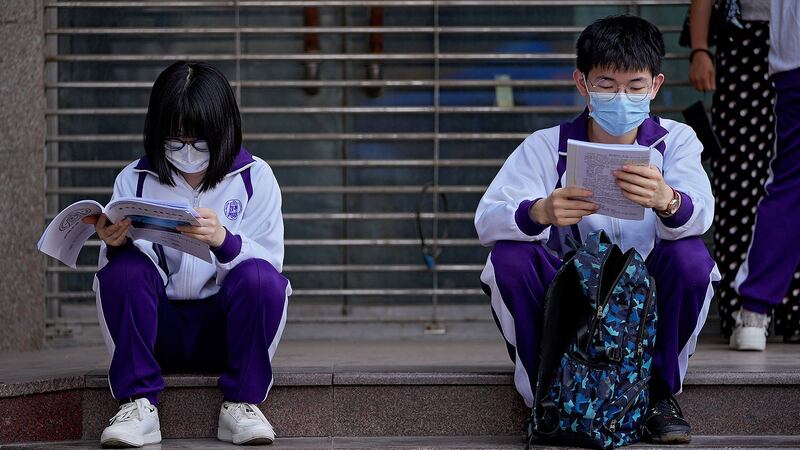 资料图片:2021 年 6 月 7 日,在北京举行的高考统考之前,学生们在校外复习课本。(美联社)
