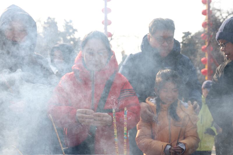 People hold incense sticks as they pray at Dongyue temple in Beijing, Jan. 30, 2025.