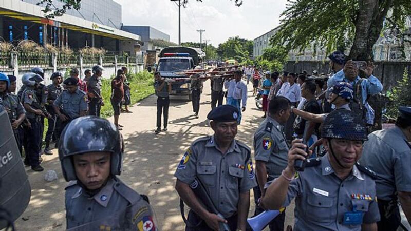 Police personnel stand guard along a street near the Chinese-owned Fu Yuen Garment Company Ltd. factory after armed thugs beat up and hospitalized some workers on strike, on the outskirts of Yangon, Oct. 15, 2018.