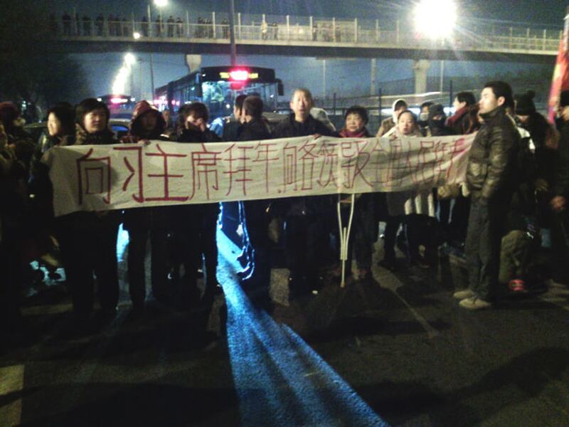 2014年1月31日，逃出馬家樓的訪民手持橫幅，在馬路中央向習近平拜早年。 （現場訪民攝）