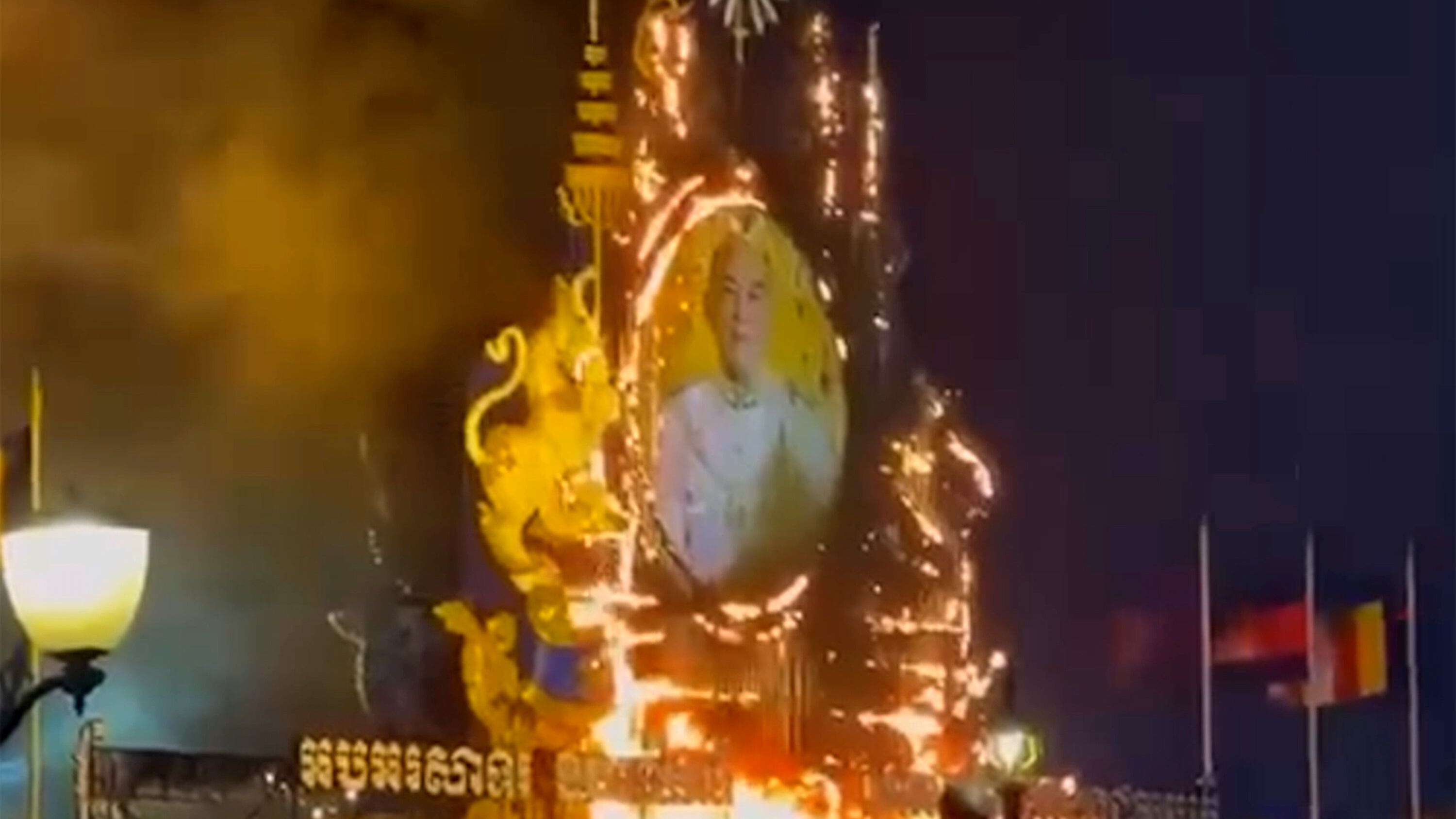 In this image made from video, a large portrait display of Cambodia's King Norodom Sihamoni is on fire during New Year celebrations in front of the Royal Palace in Phnom Penh, Jan. 1, 2025.
