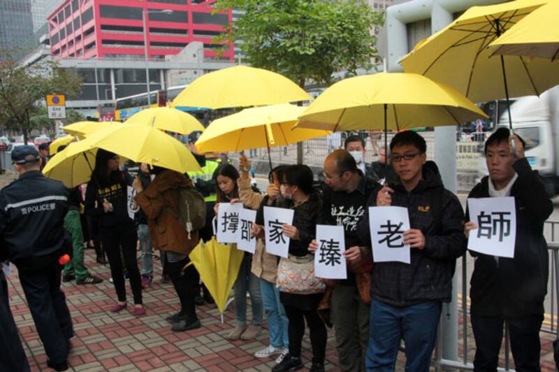 佔中支持者在三子自首走向警署的路上舉起黃傘。（粵語部文宇晴攝）