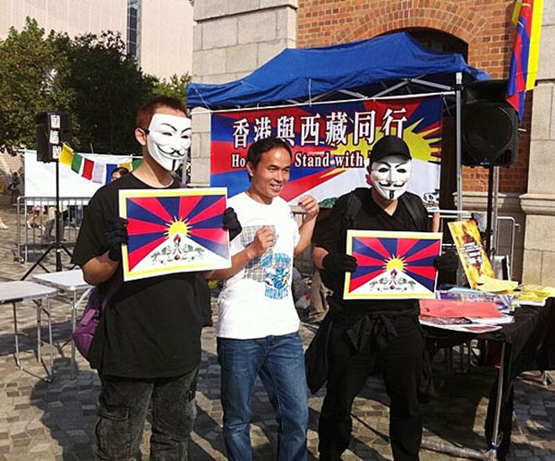 香港與西藏同行組織3月10日在尖沙咀舉行紀念活動,戴面具青年手持雪山獅子旗圖案拍照。(照片來自香港與西藏同行)