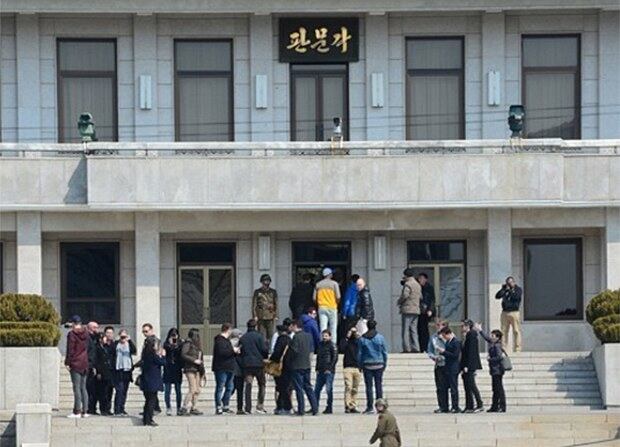 북한을 방문한 외국인 관광객들이 북측 판문각에서 판문점을 보고 있다. 