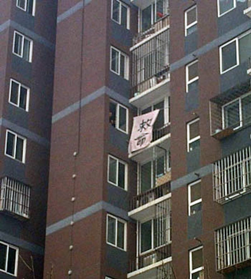 在北京上訪的吉林訪民郭洪偉，被圍困在家中近一周，他在窗外掛出求救的橫幅。(照片由民生觀察劉飛躍提供)