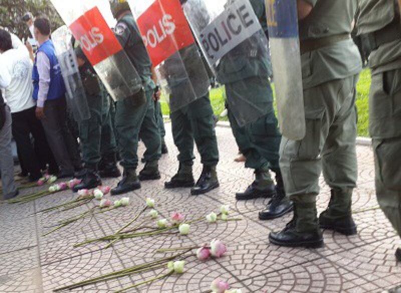 Young people lay lotus flowers at the feet of riot police stationed in Phnom Penh, Sept. 6, 2013. Photo credit: RFA.
