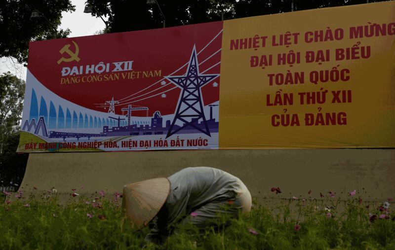 Hình minh họa. Một công nhân đang chăm vườn hoa ngay trước tấm biển chào mừng đại hội đảng ở Hà Nội hôm 8/1/2016