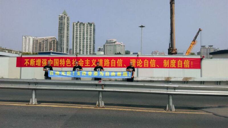 2014年11月3日，謝文飛和孫立勇、王默、孫濤、漁夫穿著黑衫，在廣州街頭拉橫幅聲援香港的公民抗命。（謝文飛推特）