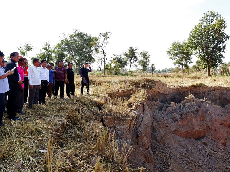 Khammouane Province Governor Vanxay Phongsavanh, left, and his delegation inspect a sinkhole in Pakpeng village, Laos, Dec. 4, 2024.