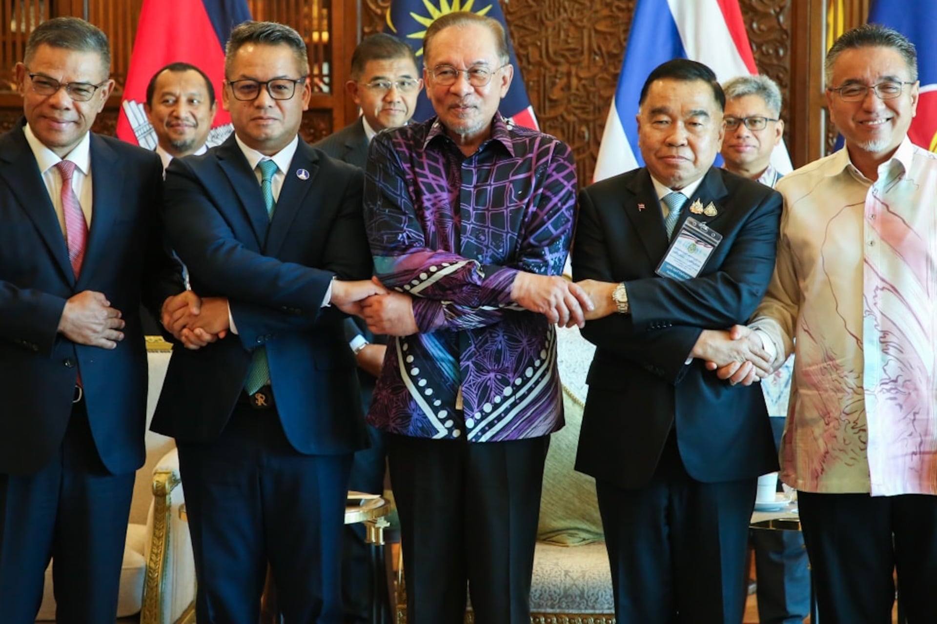 Thai Deputy Defence Minister Nattaphon Narkphanit (R), Malaysian Prime Minister Anwar Ibrahim
(C) and Cambodian Defence Minister General Tea Seiha (L) join hands for a group photo ahead of the Ex-traordinary General Border Committee (GBC) to discuss border dispute between Thailand and Cambodia, in Kuala Lumpur on August 7, 2025.