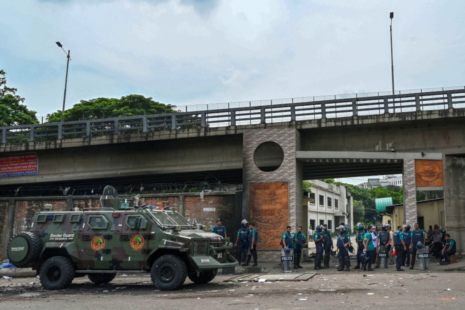 Bangladesh police stand guard at the headquarters of state broadcaster Bangladesh Television station after students set it on fire one day earlier, July 19, 2024. (Munir Uz Zaman/AFP)