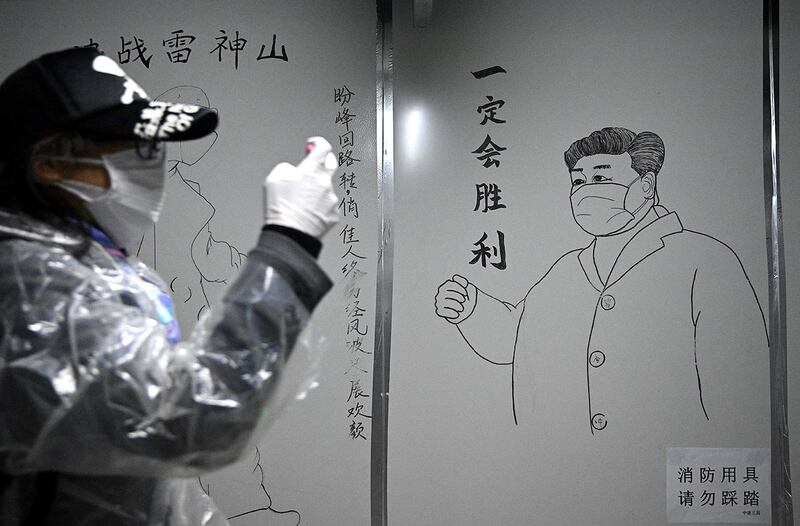 2020年初武汉爆发Covid-19新冠疫情后，湖北省武汉市雷神山医院一名工作人员在习近平戴着口罩的素描海报前。