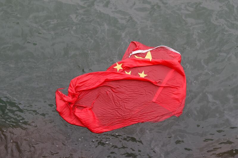 2019年8月3日，香港反送中运动一示威者，在尖沙咀天星码头将中国国旗抛入大海。（美联社）