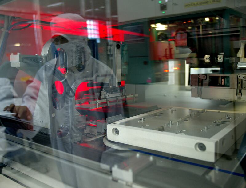 A Filipino manufacturing operator is reflected on an Automatic Mould machine at a Philippine-based semiconductor manufacturing plant in Manila Sept. 20, 2005.