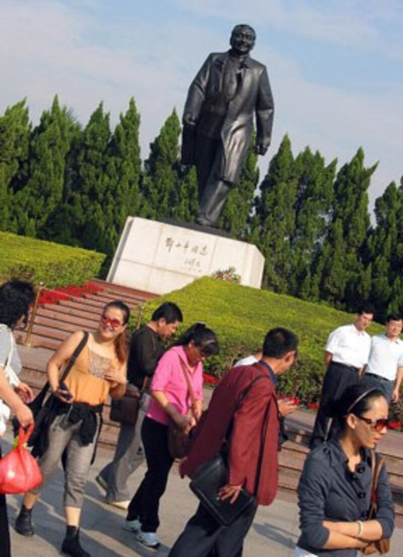 Khánh du lịch chụp ảnh với tượng Ông Đặng Tiểu Bình ở Thâm Quyến, Trung Quốc ngày 01 tháng 12, năm 2008. AFP PHOTO.
