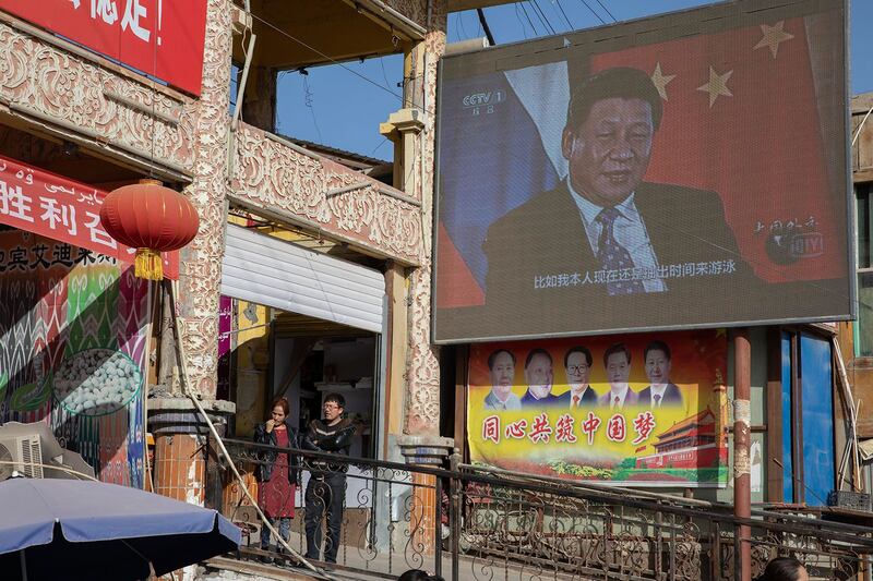 2017年11月3日，在中国新疆和田市集贸市场附近的屏幕上的习近平，下方宣传标语：同心共筑中国梦。 （美联社图片）