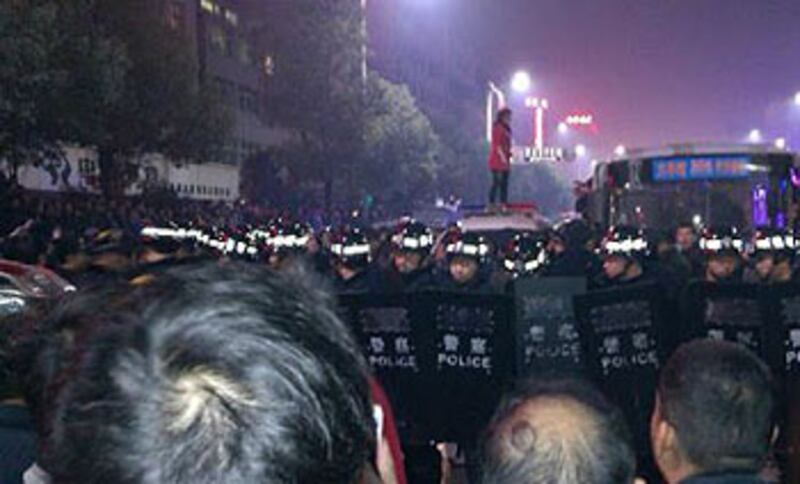 2013年1月24日，懷化市鶴城區舞水路誤傳醉警打小孩，孩子母親站到警車上抗議，而現場有上千人圍堵，過百特警手持盾牌將群眾分隔。（麥克俱樂部負責人提供）