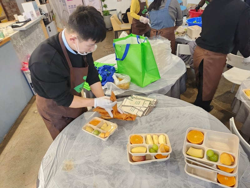 남북 봉사단체 유니시드에서 봉사자들이 과일 도시락을 만들고 있다.