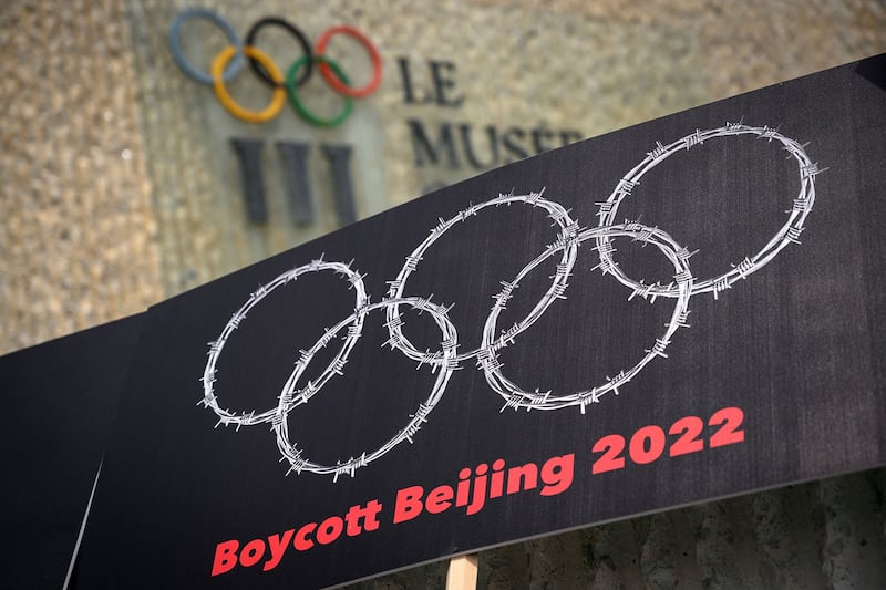 奥林匹克博物馆外,活动人士举着扺制2022北京冬奥标语牌。(法新社)